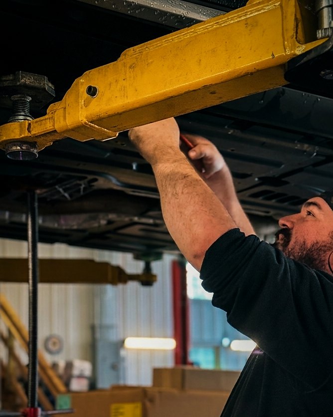 A mechanic working under a vehicle on a lift